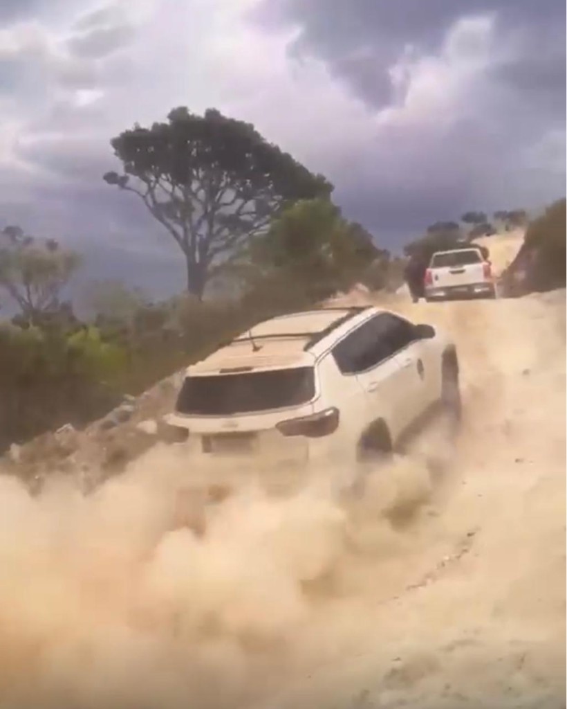 Conteúdo visual M4: Veículo 4x4 subindo estrada de terra com poeira na serra